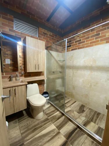 a bathroom with a toilet and a glass shower at la samara in Anapoima