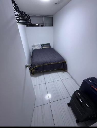 a small room with a bed and a suitcase at Studio Brasil 861 in Lima