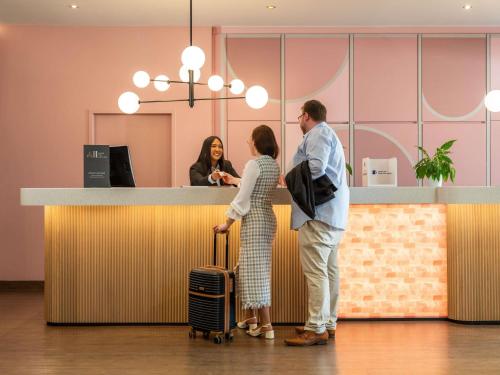 a man and a woman standing at a counter at Mercure Salzburg City in Salzburg