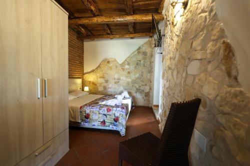 a bedroom with a bed and a stone wall at VILLA MARIA ELENA Charme Rooms sul mare in Capo Vaticano