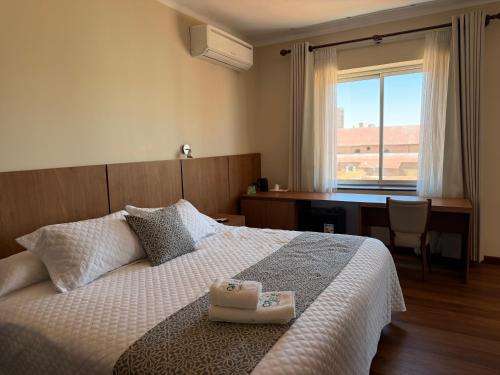 a bedroom with a bed with a desk and a window at Hotel Victoria Plaza in Tarija