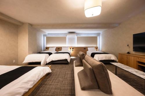 a room with three beds and a flat screen tv at ホテル雅々音 in Sasebo