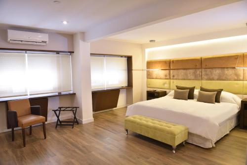 a bedroom with a large white bed and a chair at Hotel Denver Mar del Plata in Mar del Plata