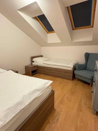 a bedroom with two beds and a blue chair at Apartmán JAMI REZIDENCIA in Spišské Podhradie