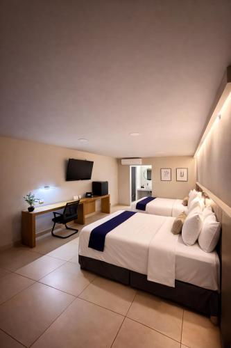 a hotel room with two beds and a desk at HOTEL LOS ROBLES in Nuevo Laredo