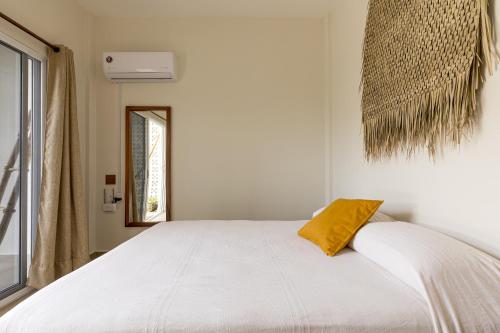 a bedroom with a white bed with a yellow pillow at Bahía Sirenas in Puerto Escondido