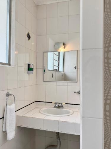 a white bathroom with a sink and a mirror at Casa Esmeralda Boutique Hotel in San José