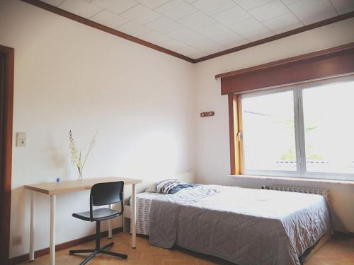 a bedroom with a bed and a desk and a window at La Doudou Maison à louer in Mons