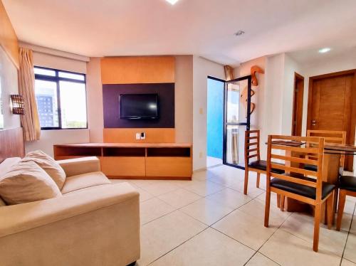 a living room with a couch and a tv and a table at Aconchegantes Flats, 1 e 2 qtos, em Ponta Negra in Natal