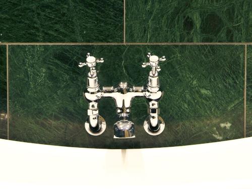 a metal sink in a bathroom with green tiles at The Wrea Head Hall Country House Hotel & Restaurant in Scarborough