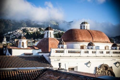 a building with a domed roof with a mountain in the background at Casa Santa Clara - Colonial Boutique Hotel in Quito