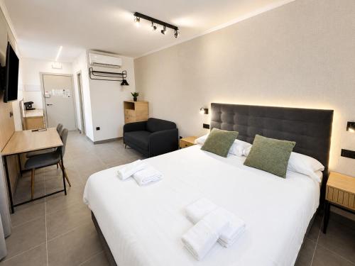 a bedroom with a large white bed and a chair at AH Rentals Suites in Vinarós