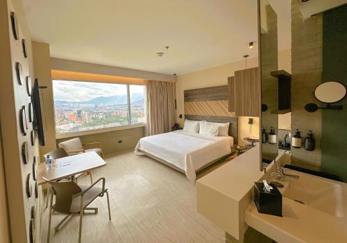 a hotel room with a bed and a desk and a sink at V Grand Hotel, a member of Radisson Individuals in Medellín