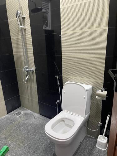 a bathroom with a white toilet and a shower at JK Residence Trincomalee in Trincomalee
