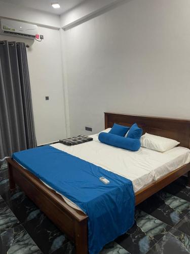 a bed with blue pillows on it in a room at JK Residence Trincomalee in Trincomalee
