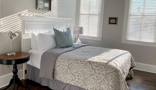 a bedroom with a bed and a table and two windows at Hotel Laurance in Luray