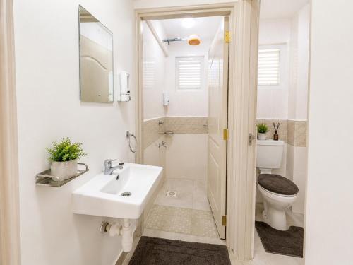 a white bathroom with a sink and a toilet at Stylish 2BR Apartment Free WiFi Near Nairobi National Park in Ongata Rongai 