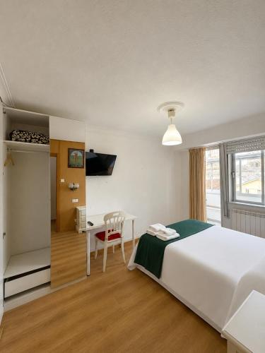 a bedroom with a bed and a table and a desk at Hostal Porta Santiago in Lugo