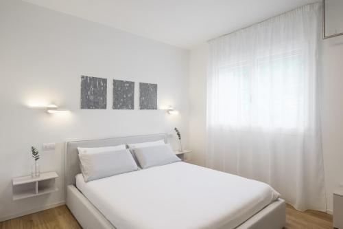 a white bedroom with a white bed and a window at el Zhìgol B&B in Farra di Soligo
