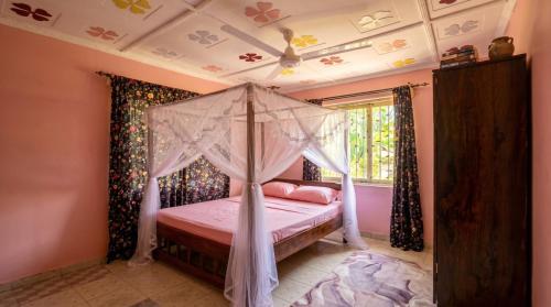 a bedroom with a canopy bed and a window at Mnchunge's Residence in Kikambala