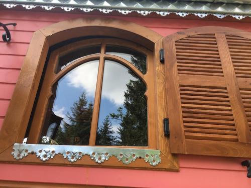 a window on the side of a pink house at La Roulotte du Fier in Annecy