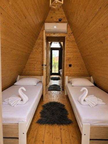 zwei Betten auf einem Dachboden mit Schwänen darauf in der Unterkunft Ocna Frame - A Frame cu Jacuzzi si Terasa in Ocna-Mureşului