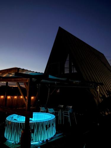 ein Gebäude mit einem Tisch und Stühlen bei Nacht in der Unterkunft Ocna Frame - A Frame cu Jacuzzi si Terasa in Ocna-Mureşului