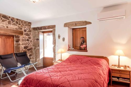 a bedroom with a red bed and two chairs at Cantinho de Caria in Caria