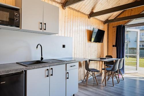 a kitchen with a sink and a table with chairs at Domki Anchor II - 200m od Morza, Klimatyzacja, Plac Zabaw, Parking in Karwia