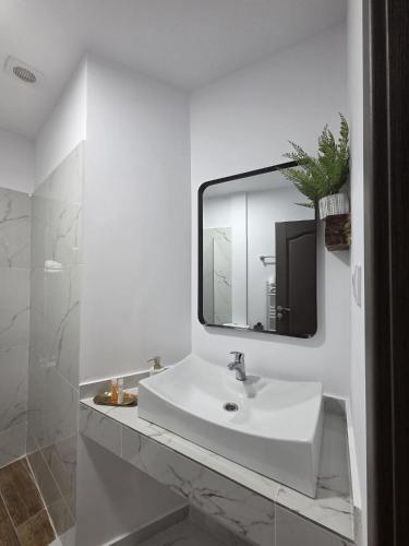 a white bathroom with a sink and a mirror at Vintage House Apart in Buzău