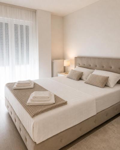 a white bedroom with a large bed with two towels on it at Veles in Banja Koviljača