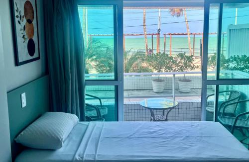 a bedroom with a bed and a view of the ocean at Flat JP Beira mar in João Pessoa
