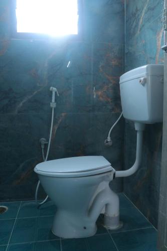 a white toilet in a bathroom with a light at Yardlin Hotel in Perunkalattu