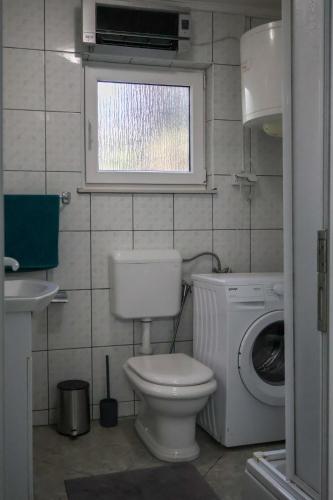 a bathroom with a toilet and a washing machine at Villa Enio in Bihać