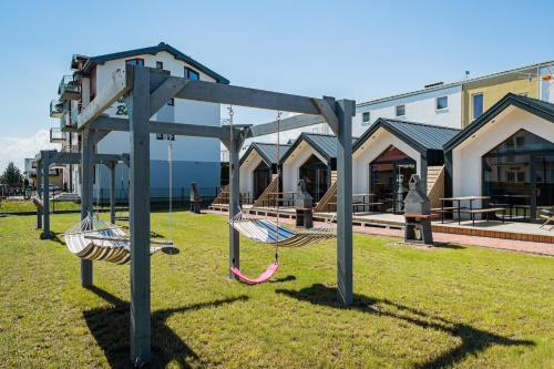 a playground with swings in the grass in front of a building at Domki Anchor II - 200m od Morza, Klimatyzacja, Plac Zabaw, Parking in Karwia