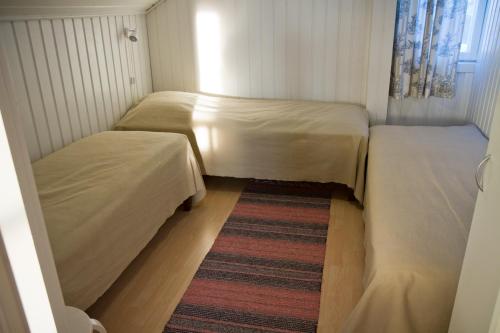 two beds in a small room with a rug at Erkin Haussi in Ilmajoki