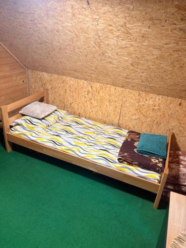 a small bed in a room with a wooden wall at Riverside Cabin in Železnička Stanica Ovčar Banja
