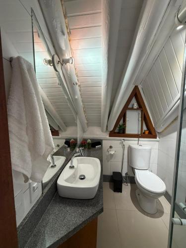 a small bathroom with a toilet and a sink at Chalé cercado pela natureza in Imbituba