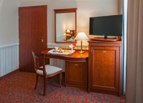 Habitación de hotel con escritorio, TV y mesa con silla. en Adria Hotel Prague, en Praga