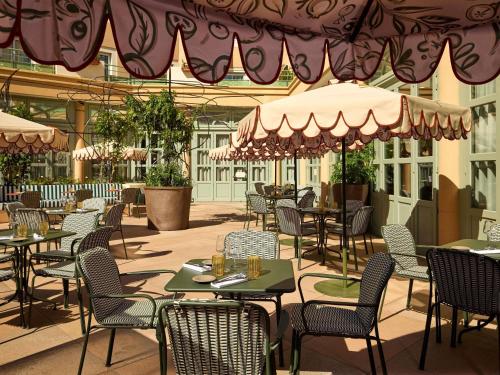 an empty restaurant with tables and chairs and umbrellas at Grand Hôtel Roi René Aix - MGallery Collection in Aix-en-Provence