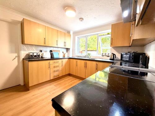 a kitchen with wooden cabinets and a black counter top at Swan View House in Littleport
