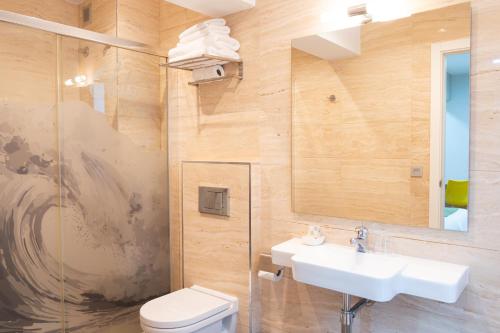 a bathroom with a sink and a toilet and a mirror at Hotel Olatu in Zarautz