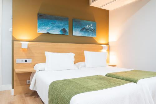 a hotel room with two beds and two paintings on the wall at Hotel Olatu in Zarautz