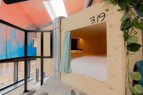 a bedroom with a bed in a room with windows at Kumo Hostels in Groningen