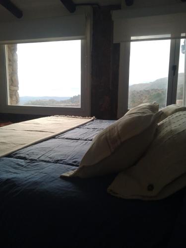 a bedroom with a bed with two large windows at Oveja Mansa in La Cumbre