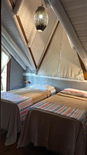 a attic room with two beds and a ceiling at Chalé cercado pela natureza in Imbituba