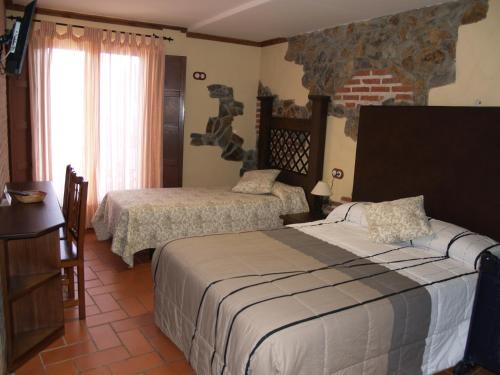 a bedroom with two beds and a brick wall at Hotel Rural El Rocal in Ledesma