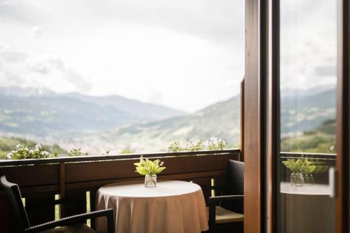 a table with a vase of flowers on a balcony at WEINBERG APARTMENTS & Brixen Südtirol Guest Pass in Natz-Schabs