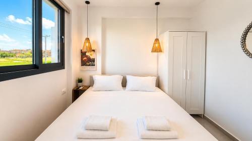 a white bedroom with two beds and a window at Ambra Luxury Suite 15 in Kallithea Halkidikis
