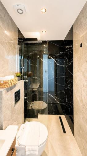 a bathroom with a toilet and a glass shower at Ambra Luxury Suite 15 in Kallithea Halkidikis